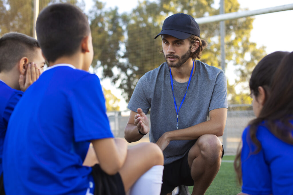 side-view-football-trainer-helping-kids